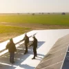 Ingenieros en tejado industrial revisando planta solar fotovoltaica