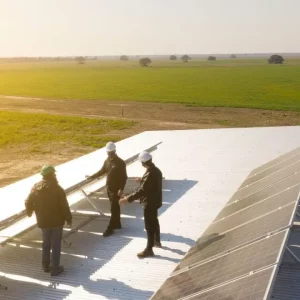 Ingenieros en tejado industrial revisando planta solar fotovoltaica
